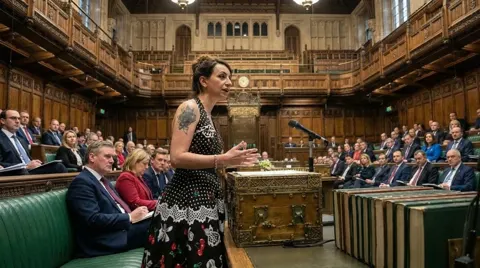 Still from The Sea Candle: Diddy Wheldon addresses a packed House of Commons chamber