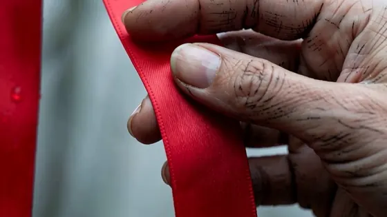 Still from The Trees: close-up of a hand holding a red ribbon