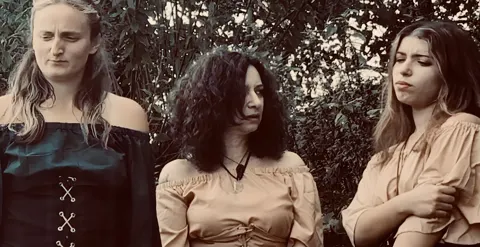 Still from Trapped in Their Dreams: three women in period dresses outdoors
