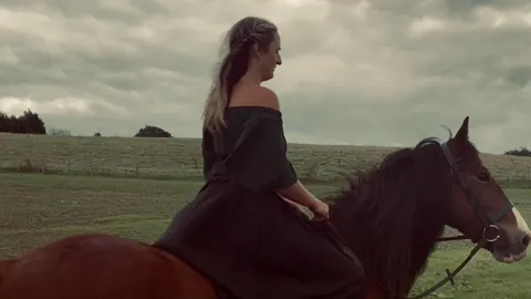 Still from Trapped in Their Dreams: a woman riding a bay horse across open fields