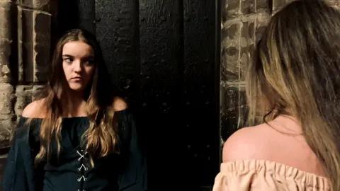 Still from Trapped in Their Dreams: two women in period costume in a dark interior