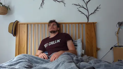 Still from Trapped in Their Dreams: a man sitting up in bed